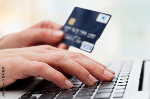 Photo: Hand typing on laptop with credit card. Hand typing on laptop with credit card.