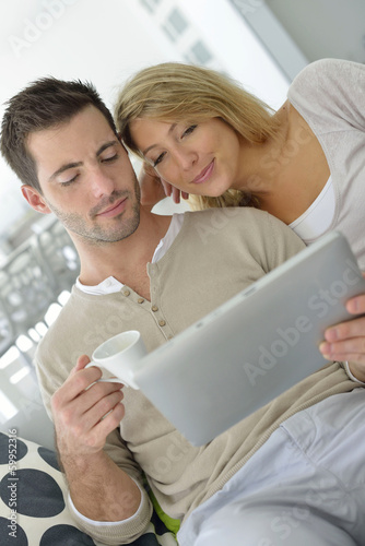 Photo: Cheerful couple using digital tablet at home Cheerful couple using digital tablet at home