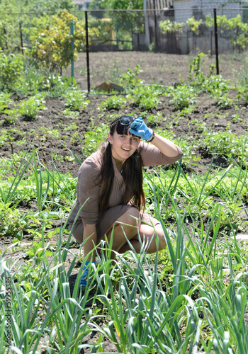 Photo: Happy young woman gardening in a warm sunny day Happy young woman gardening in a warm sunny day