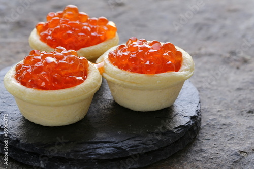 Photo: gourmet tartlets with red caviar on a stone plate gourmet tartlets with red caviar on a stone plate