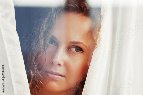 Photo: Sad beautiful woman looking out the window Sad beautiful woman looking out the window