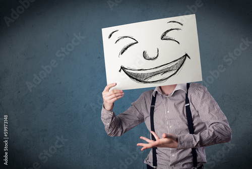 Photo: Businessman holding a paper with smiley face in front of his hea Businessman holding a paper with smiley face in front of his hea