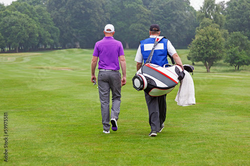 Photo: Golfer and caddy walking up a fairway Golfer and caddy walking up a fairway