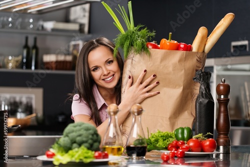Photo: Young woman with grocery bag full of vegetables Young woman with grocery bag full of vegetables