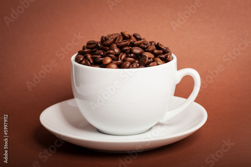 Photo: Coffee beans in cup on brown background Coffee beans in cup on brown background
