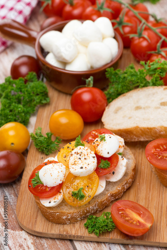 Photo: ciabatta with mozzarella and colorful cherry tomatoes on board ciabatta with mozzarella and colorful cherry tomatoes on board
