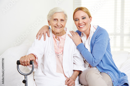 Photo: Frau umarmt alte Seniorin zu Hause Frau umarmt alte Seniorin zu Hause