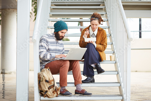 Photo: Hipster couple using computer and eating lunch outdoors Hipster couple using computer and eating lunch outdoors