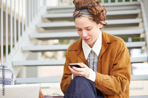 Photo: Young redhead hipster woman using smartphone Young redhead hipster woman using smartphone