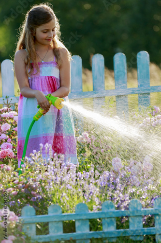 Photo: Watering, flower garden - girl watering roses Watering, flower garden - girl watering roses