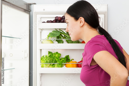 Photo: Young woman looking into a refrigerator Young woman looking into a refrigerator