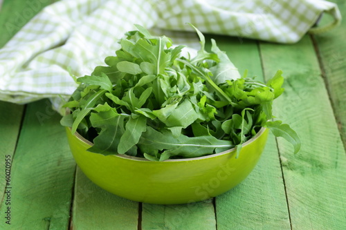Photo: bowl of green salad with arugula on wooden table bowl of green salad with arugula on wooden table