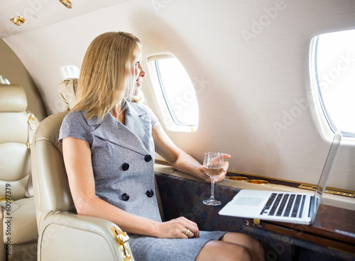Photo: Businesswoman Looking Through Window Of Private Jet Businesswoman Looking Through Window Of Private Jet
