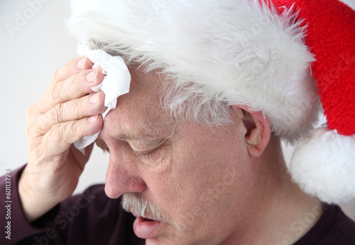 Photo: senior in Santa hat mops his brow senior in Santa hat mops his brow