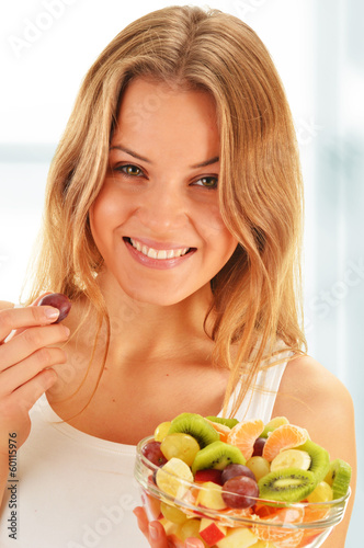 Photo: Young woman eating fruit salad Young woman eating fruit salad