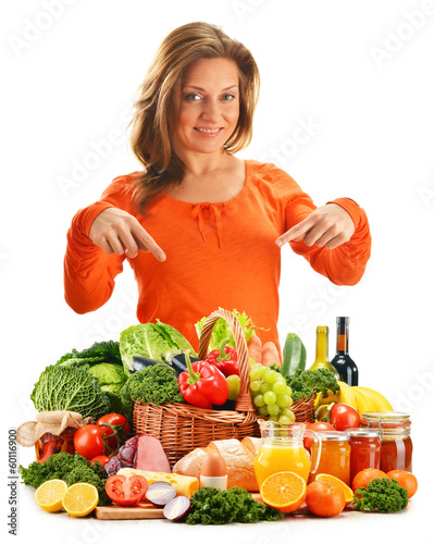 Photo: Young woman with variety of grocery products isolated on white Young woman with variety of grocery products isolated on white