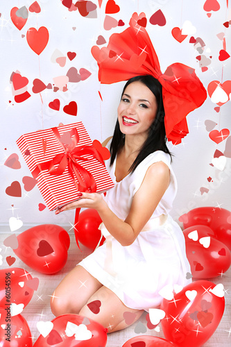 Photo: Attractive young woman with gift and balloons in room Attractive young woman with gift and balloons in room