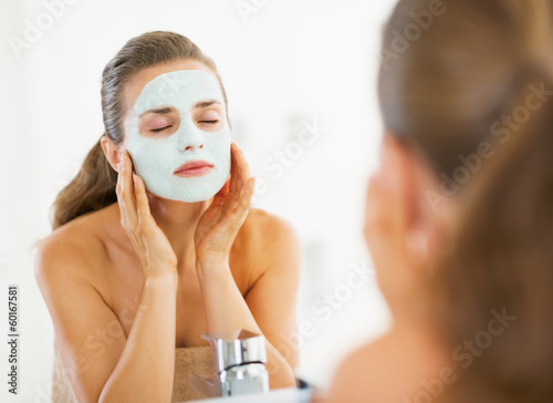 Photo: Young woman applying facial mask in bathroom Young woman applying facial mask in bathroom