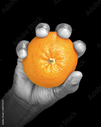 Photo: Hand holding an orange - partially monochrome, low key Hand holding an orange - partially monochrome, low key
