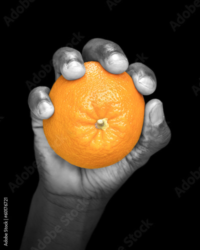Photo: Hand holding an orange - partially monochrome, low key Hand holding an orange - partially monochrome, low key