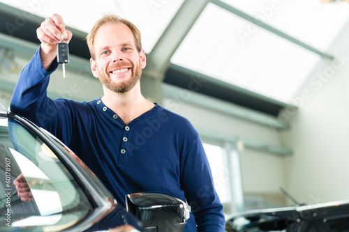 Photo: Kunde mit Autoschlüssel vor Auto in Autohaus Kunde mit Autoschlüssel vor Auto in Autohaus