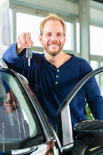 Photo: Kunde mit Autoschlüssel vor Auto in Autohaus Kunde mit Autoschlüssel vor Auto in Autohaus