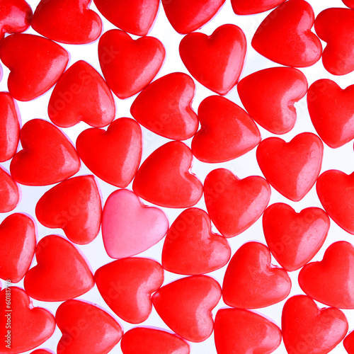 Photo: Pink heart between a pile of red hearts. Candy Hearts background Pink heart between a pile of red hearts. Candy Hearts background