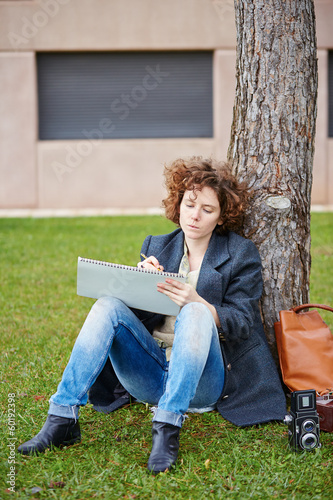 Photo: Female redhead art student drawing outdoors Female redhead art student drawing outdoors