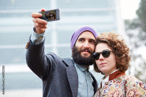 Photo: Couple taking a photograph of themselves with a smartphone Couple taking a photograph of themselves with a smartphone