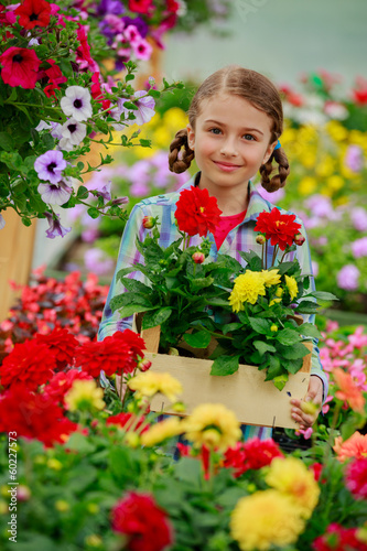Photo: Planting - Lovely girl holding flowers in garden center Planting - Lovely girl holding flowers in garden center