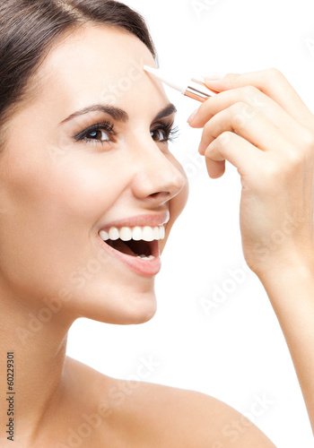 Photo: Smiling woman applying concealer on face, isolated Smiling woman applying concealer on face, isolated