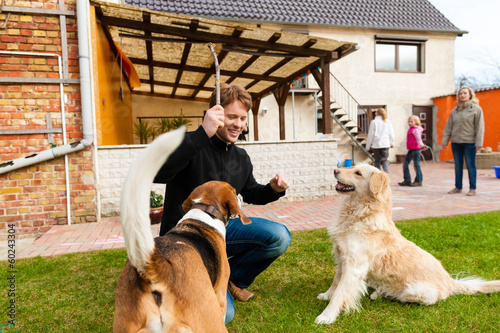 Photo: Young man playing with his dogs in garden Young man playing with his dogs in garden