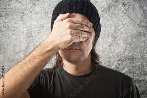 Photo: Casual Man with Black Cap covering face Casual Man with Black Cap covering face