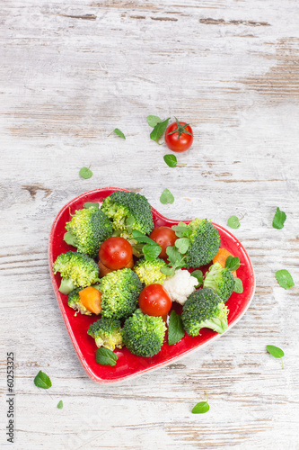 Photo: Raw vegetable in heart shaped plate. Diet concept. Macrobiotic. Raw vegetable in heart shaped plate. Diet concept. Macrobiotic.