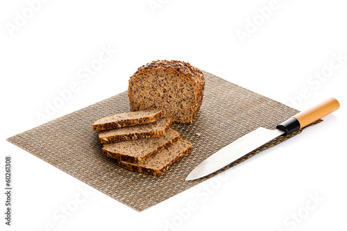 Photo: Fresh bread being sliced on a wooden cutting board with a bread Fresh bread being sliced on a wooden cutting board with a bread