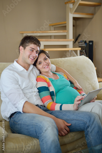 Photo: pregnant couple at home using tablet computer pregnant couple at home using tablet computer