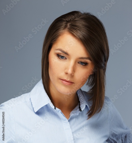 Photo: Thoughtful beautiful young brunette woman in blue shirt Thoughtful beautiful young brunette woman in blue shirt