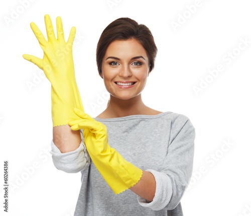 Photo: Beautiful cheerful brunette woman pulling on rubber gloves Beautiful cheerful brunette woman pulling on rubber gloves