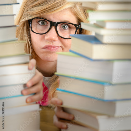 Photo: Desperate student teenager look from behind books Desperate student teenager look from behind books