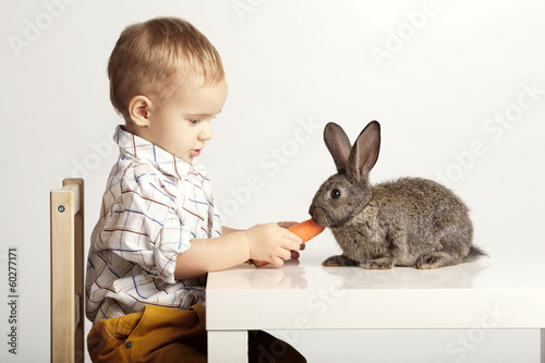 Photo: Small pretty boy feeding rabbit with carrot Small pretty boy feeding rabbit with carrot