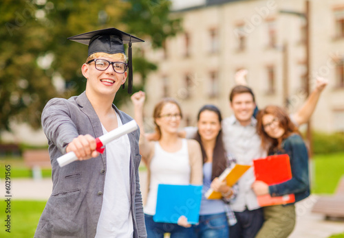 Photo: smiling teenage boy in corner-cap with diploma smiling teenage boy in corner-cap with diploma