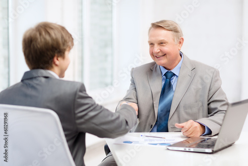 Photo: older man and young man shaking hands in office older man and young man shaking hands in office
