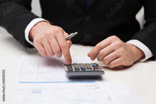 Photo: close up of businessman with papers and calculator close up of businessman with papers and calculator