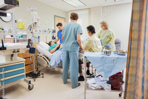 Photo: Medical Team Operating Pregnant Woman While Husband Standing By Medical Team Operating Pregnant Woman While Husband Standing By