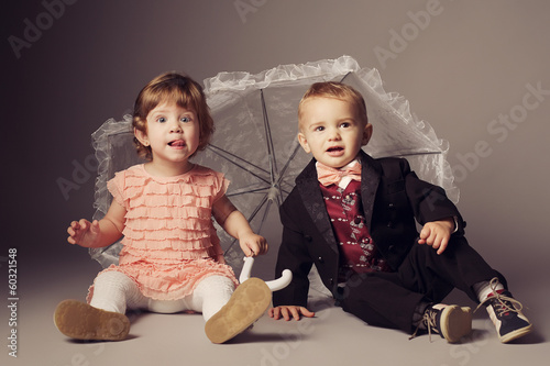 Photo: little funny boy and girl sitting under umbrella little funny boy and girl sitting under umbrella
