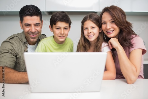Photo: Portrait of a smiling couple with kids using laptop Portrait of a smiling couple with kids using laptop