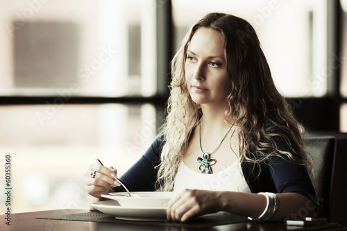 Photo: Happy young woman eating a soup at restaurant Happy young woman eating a soup at restaurant
