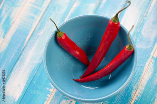 Photo: Red chili peppers in a turquoise glass bowl, horizontal shot Red chili peppers in a turquoise glass bowl, horizontal shot