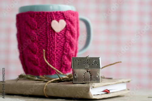 Photo: Blue cup in a pink sweater standing on an old notebook Blue cup in a pink sweater standing on an old notebook