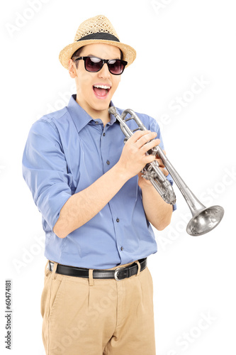 Photo: Excited young musician wearing sunglasses and holding a silver t Excited young musician wearing sunglasses and holding a silver t